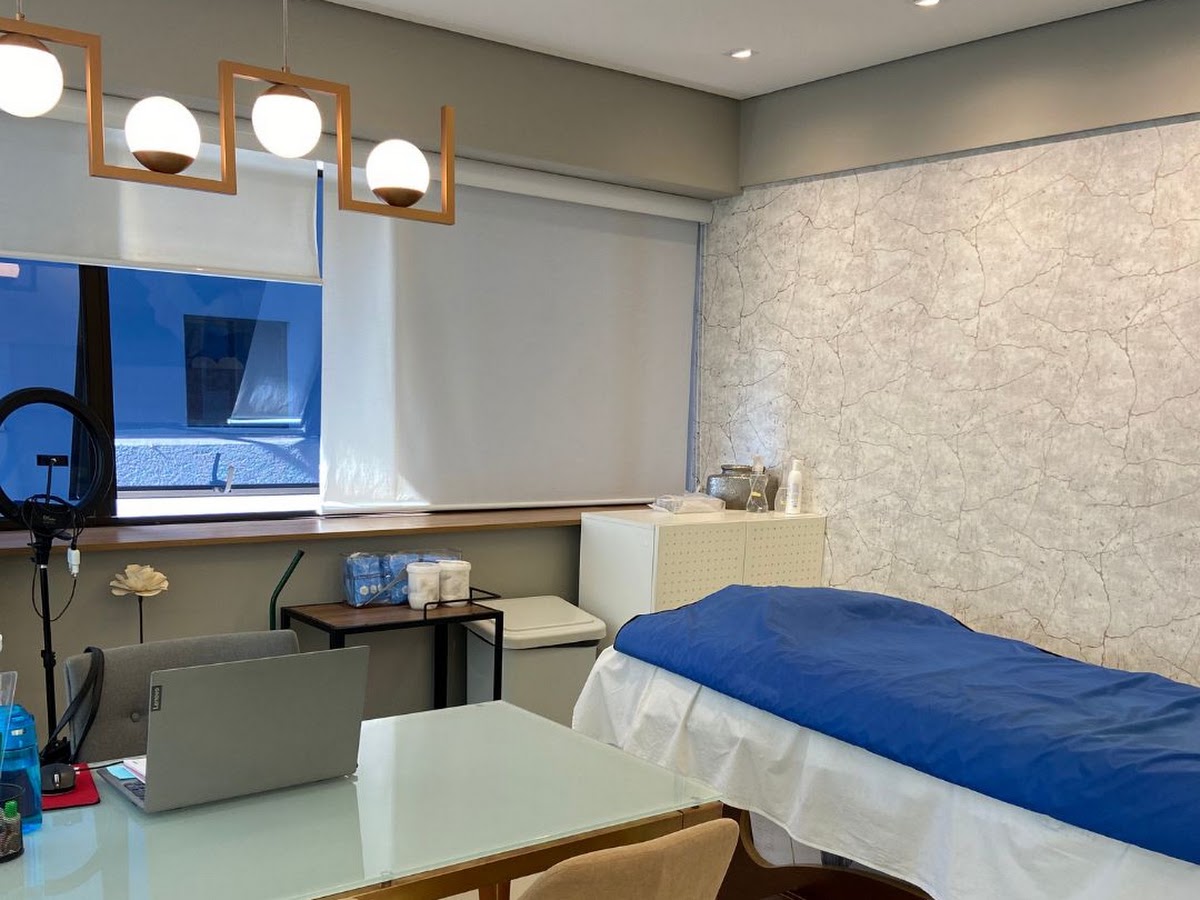Sala de atendimento clara e privativa, com maca, ring light e luminária moderna