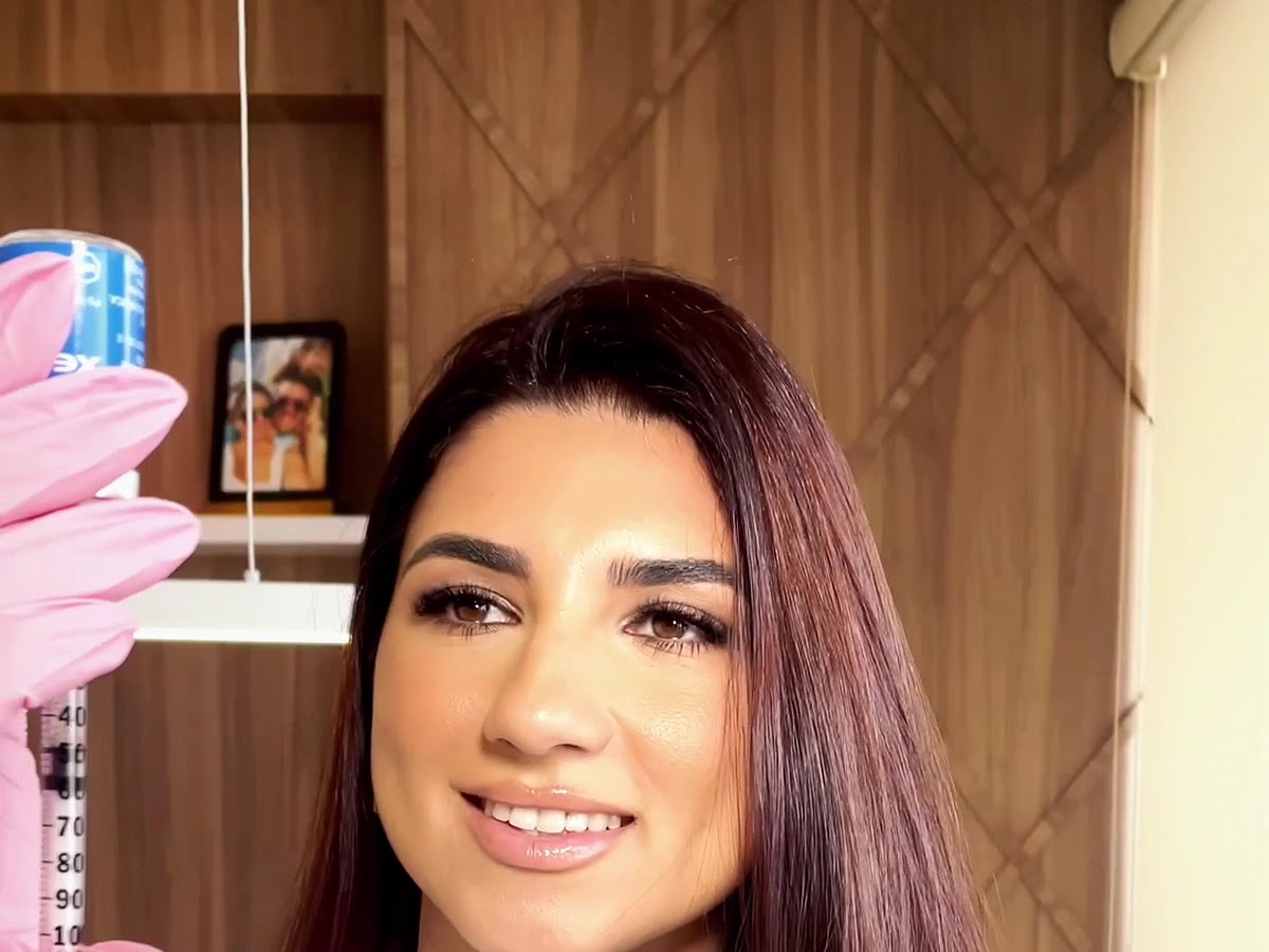 Registro real no consultório: paciente sorrindo durante preparo de procedimento facial com a Dra. Julliane